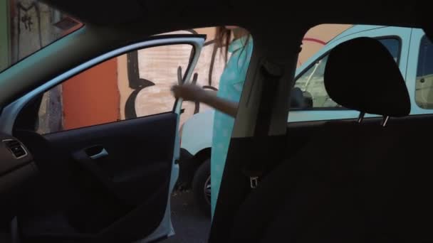 Woman put a denim jacket on the car seat and sits down on the drivers seat, intending to start the engine - Filmagem, Vídeo