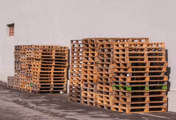 Pallets stacked on top of each other on the ground and against a white wall - Photo, Image