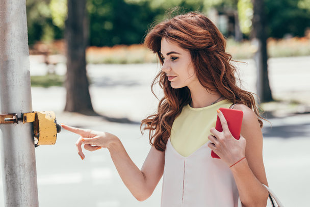 Seitenansicht junge Frau drückt Taste auf Zebrastreifen - Foto, Bild