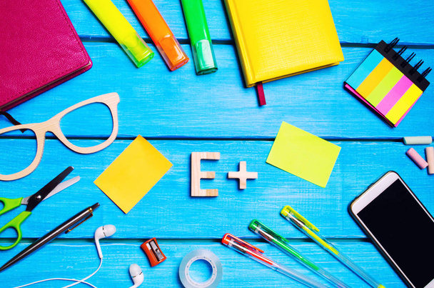 low mark, ball, e, plus, school supplies in the school desk, stationery, school concept, blue background, creative chaos, space for text, markers, pens, notepads, stickers. - Photo, Image
