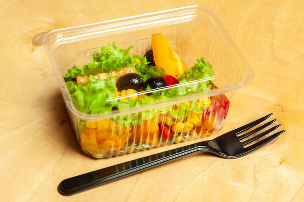 Ensalada de verduras en una caja de plástico con tenedor de plástico
 - Foto, imagen