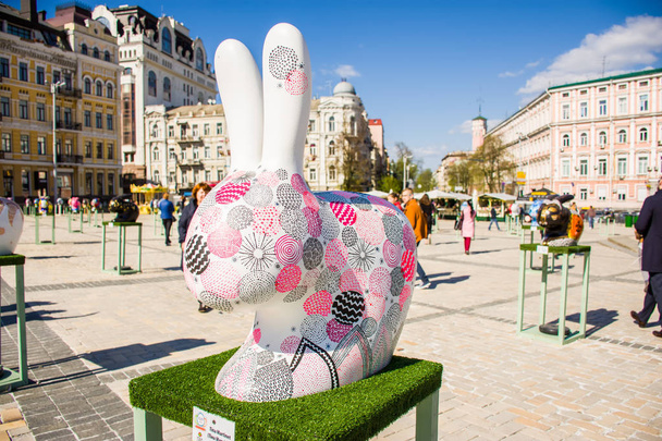 The figure of a white Easter Bunny with painted Easter eggs on it in pink and purple color. Beautiful Easter decoration art. Kyiv (Kiev), Ukraine.  - Фото, изображение