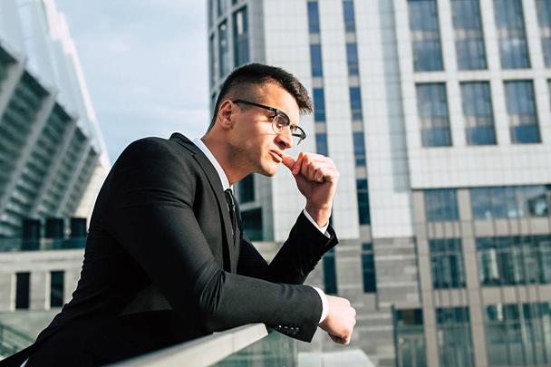 Determined young businessman in glasses on modern city background - Foto, Imagen