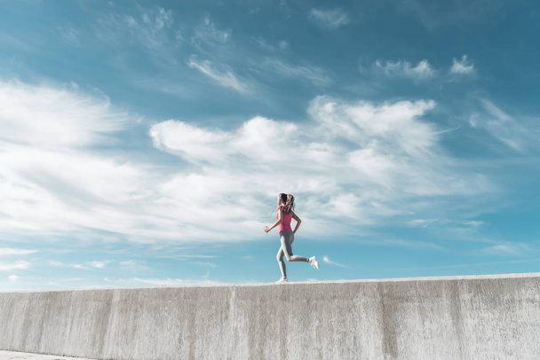 a young girl runs under the blue sky, leads an active and healthy lifestyle - Foto, afbeelding