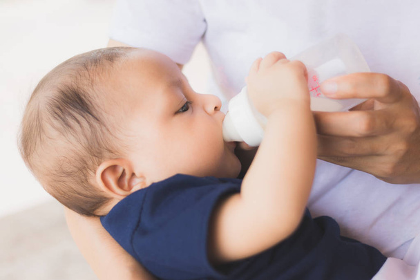 infant baby on being fed by her mother drinking milk from bottle.asian newborn - Foto, Bild