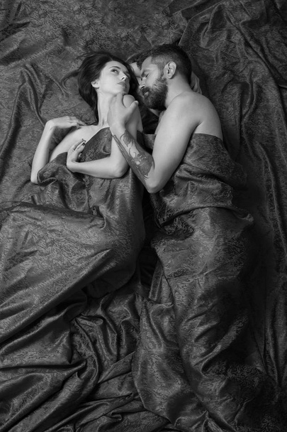 Love and sex concept. Couple in love lies on burgundy sheets hugging - Foto, imagen