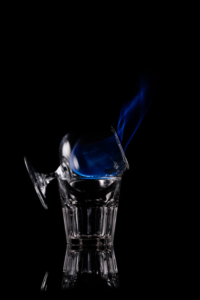 primer plano vista de alcohol sambuca bebida quema en vidrio sobre fondo negro
 - Foto, imagen