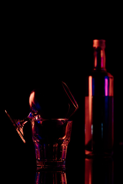close up view of bottle and glasses with sambuca alcohol drink on black background - Foto, Imagen