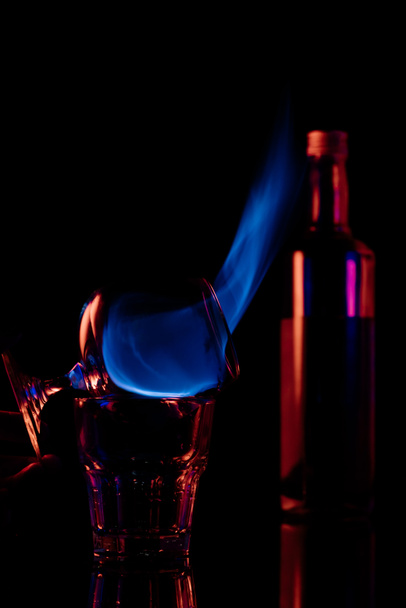 close up view of alcohol sambuca drink burning in glass on black background - Fotoğraf, Görsel