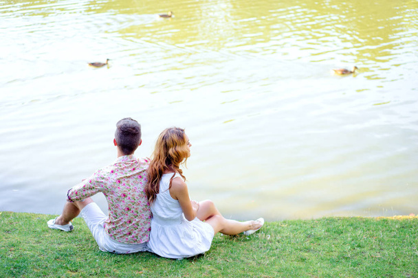 Loving couple sitting together on grass near the lake. - Photo, Image