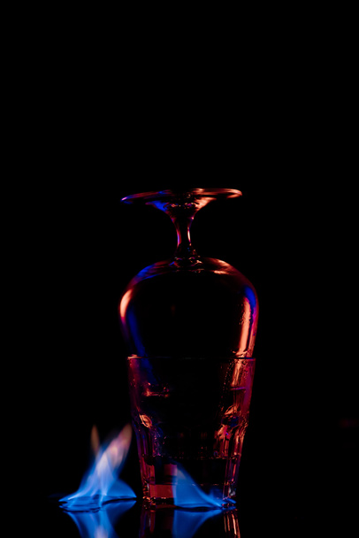 close up view of glasses and burning sanbuca alcohol drink around on black background - 写真・画像