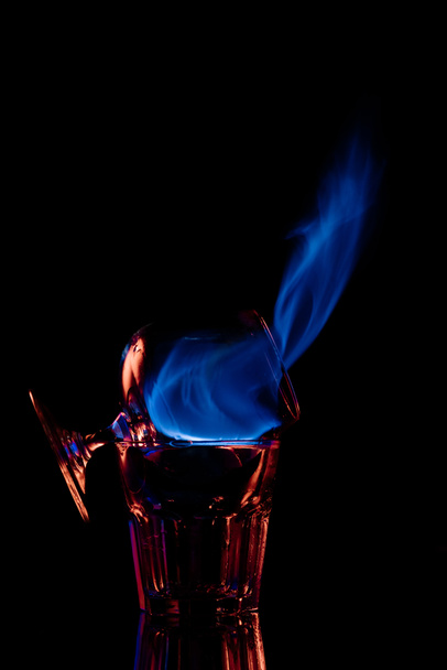 close up view of alcohol sambuca drink burning in glass on black background - Zdjęcie, obraz
