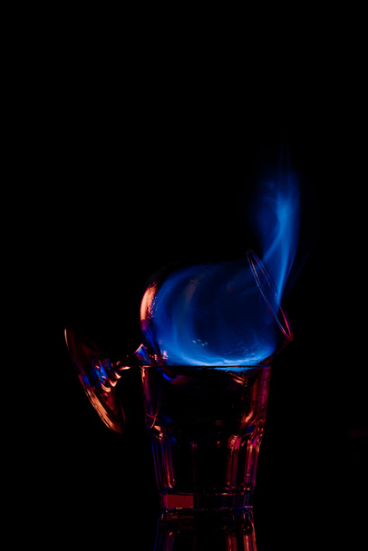 close up view of alcohol sambuca drink burning in glass on black background - Foto, afbeelding