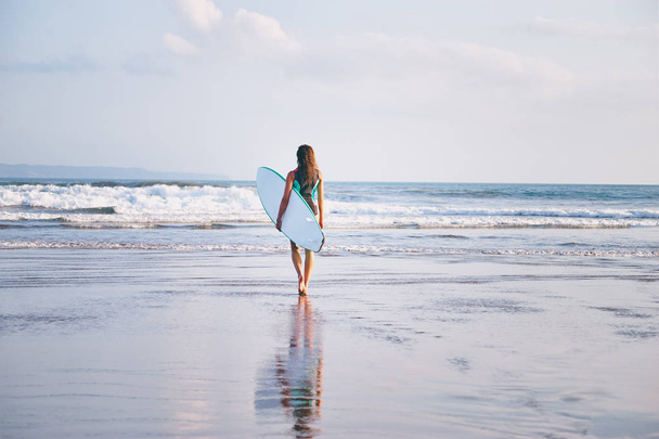 Pretty young woman holding surf board on the sea shore. - Фото, зображення