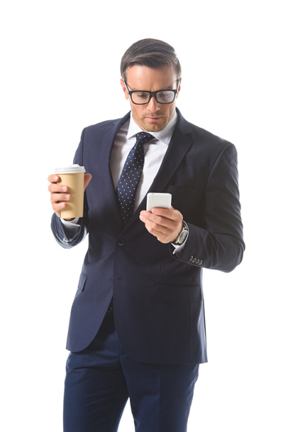 бизнесмен в очках проверка смартфона и проведение бумажной чашки кофе изолированы на белом фоне
  - Фото, изображение