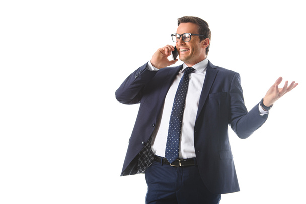 smiling businessman in eyeglasses talking on smartphone and gesturing by hand isolated on white background  - Фото, зображення