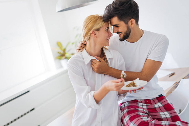 Cute young cheerful couple spending time at home eating cake - Photo, Image
