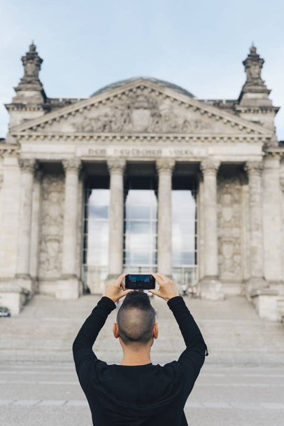 primo piano di un giovane caucasico, visto da dietro, che fotografa la facciata dell'edificio del Reichstag a Berlino, Germania, con il suo smartphone
 - Foto, immagini