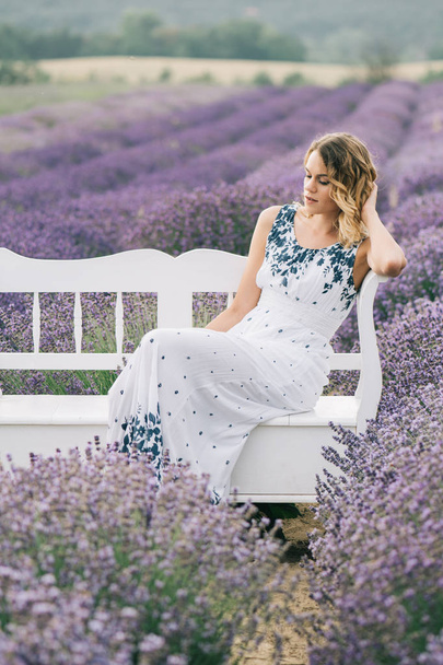 Beautiful woman sitting on bench at lavender field. - Fotoğraf, Görsel