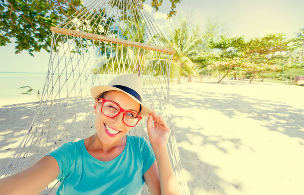 Young pretty woman in hat laying in hammock on the beach. - Фото, зображення