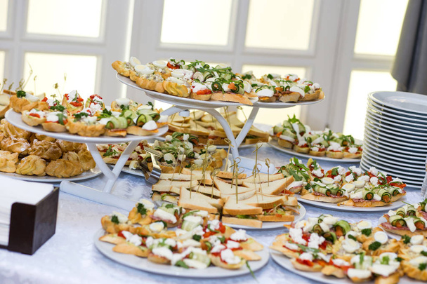 dovolenkový stůl servírovaný různými kanapkami, sendviči, občerstvení připravené k jídlu v restauraci - Fotografie, Obrázek