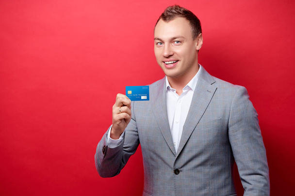 Handsome young man in suit showing plastic card - Foto, Imagen