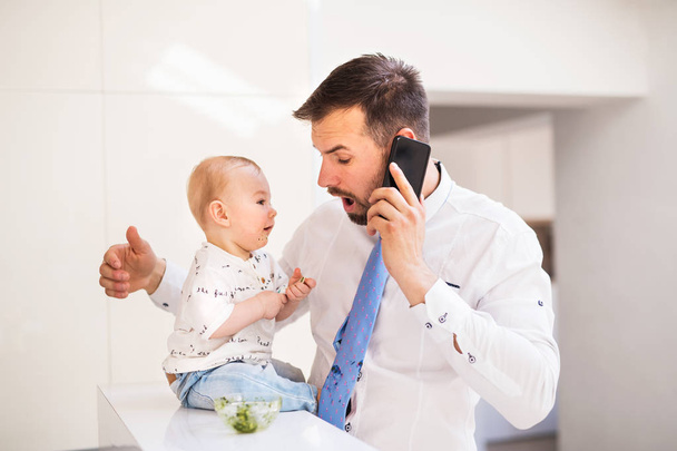 A baby boy making his fathers tie dirty when eating. - 写真・画像