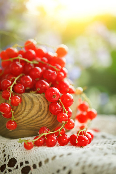 Ripe red currant on a wooden table in the garden. - Foto, Bild