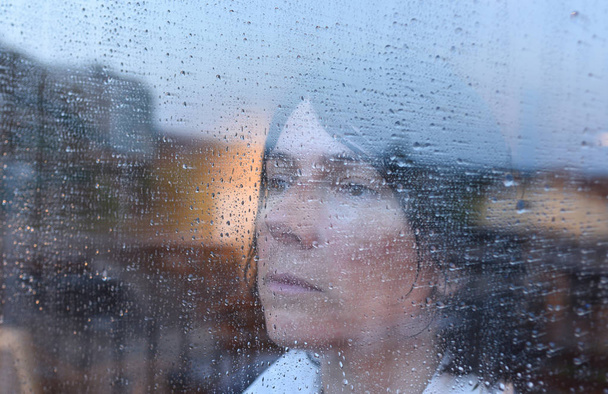 Yağmurlu bir günde pencereden dışarı bakarak kadın - Fotoğraf, Görsel