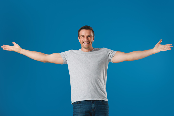 веселий чоловік стоїть з відкритими руками і посміхається на камеру ізольовано на синьому
 - Фото, зображення