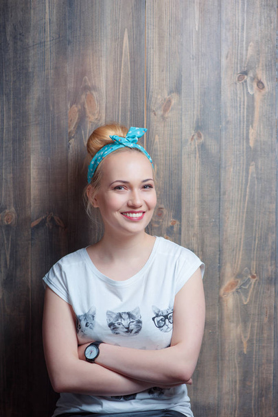 Portrait of young attractive smiling woman looking at camera leaning on wooden wall. - Fotó, kép