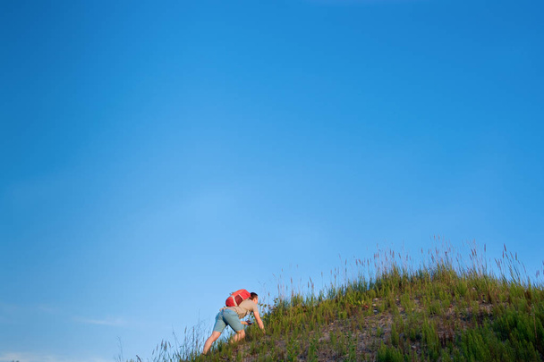 traveler with orange backpack hiking in the hills on blue sky background - Fotó, kép