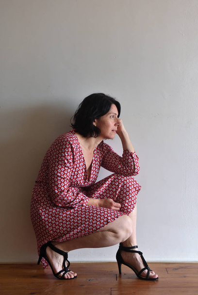 γυναίκα κάθεται οκλαδόν μπροστά από τοίχο ura - Φωτογραφία, εικόνα