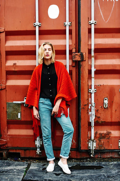 blonde woman wearing stylish clothes posing on background of red cargo container - Foto, Imagem