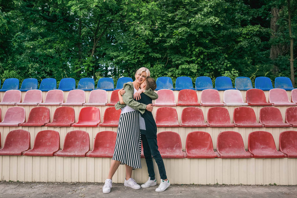 full length view of beautiful happy mother and son hugging on stadium - Fotografie, Obrázek