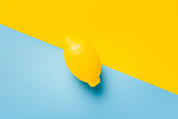 Citronová šťáva ovoce na pastelově modré a žluté pozadí. Minimální letní koncept. Byt leží. Vitamín C. - Fotografie, Obrázek