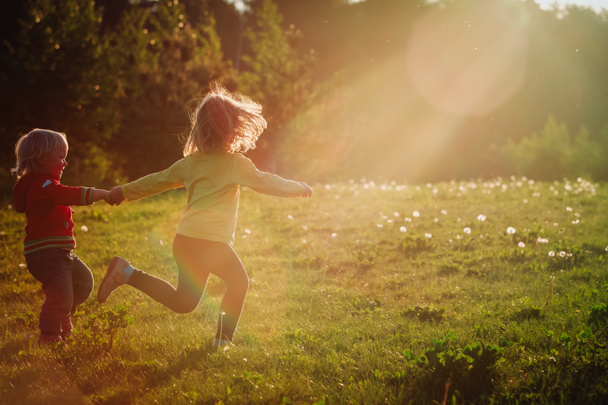 niños felices corren jugar en la naturaleza puesta del sol
 - Foto, Imagen