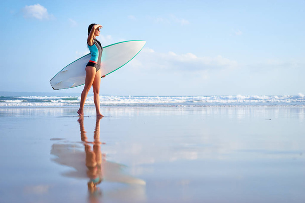 Pretty young woman holding surf board on the sea shore. - Valokuva, kuva