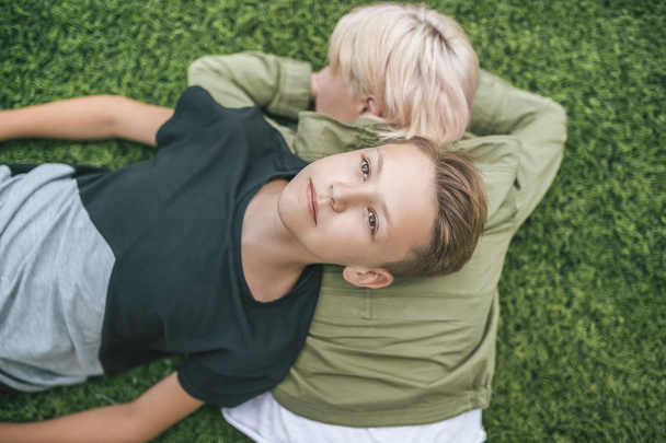 top view of beautiful mother and son lying together on green grass  - Valokuva, kuva