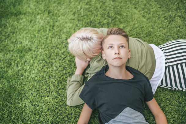 вид зверху на матір і сина, що лежить разом на зеленій траві
  - Фото, зображення