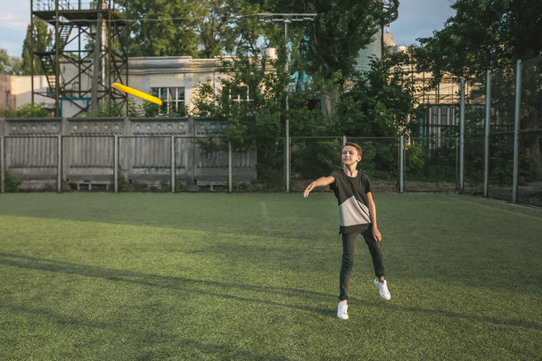 visão comprimento total do menino jogando disco voador no gramado verde
 - Foto, Imagem