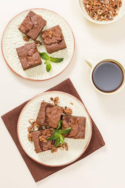 Brownie édes csokoládé desszert dió és tervezett levelek kézműves lemez és csésze fekete kávé pasztell bézs háttér - szép banner, a finom barna sült tészta. - Fotó, kép