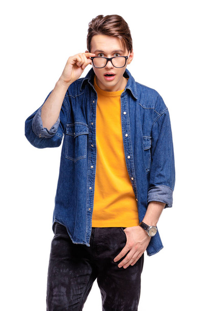 Studio portrait of amazed young man  holding eyeglasses - Photo, image