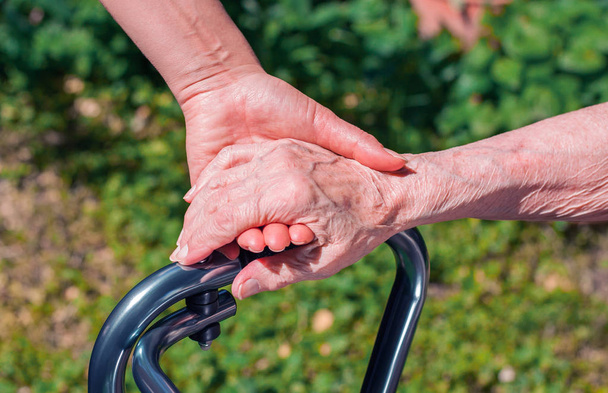 Senhora dando uma mão amiga para uma mulher idosa com walker
.  - Foto, Imagem
