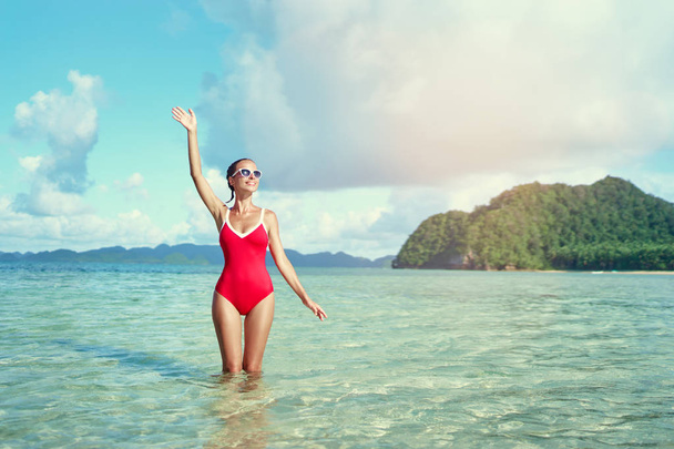 Outdoor portrait of pretty young woman in red swimsuit on beautiful tropical beach. - Foto, imagen
