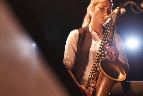 beautiful woman playing saxophone on stage  - Zdjęcie, obraz