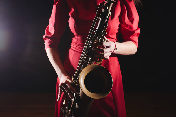 Musician woman in red dress with saxophone on stage, close-up  - Foto, Bild