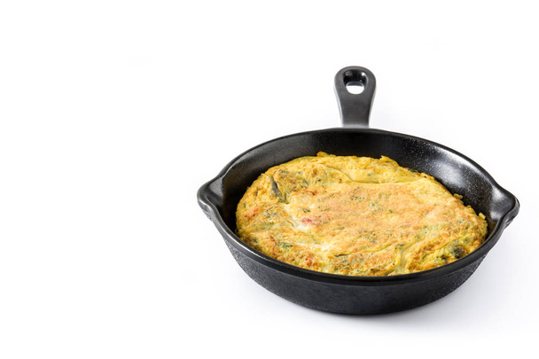 Frittata gemaakt van eieren en groenten in een ijzeren pan, geïsoleerd op een witte achtergrond. Copyspace - Foto, afbeelding