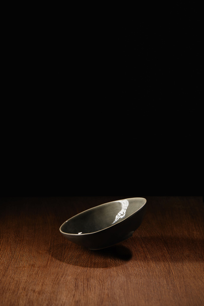 木製のテーブルの表面の上を飛んで空セラミック ボウル - 写真・画像