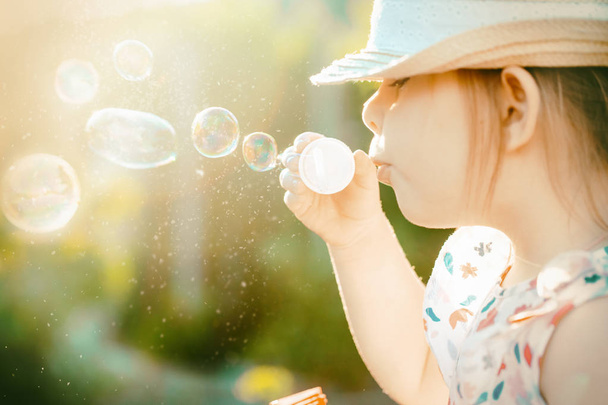 bambina che soffia bolle di sapone nel parco estivo. Tonica
 - Foto, immagini